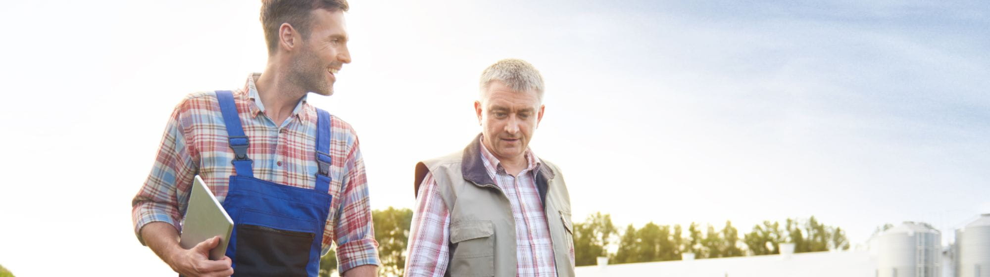 Deux agriculteurs en train de parcourir une exploitation de grandes cultures qui échangent leurs retours d’expérience.