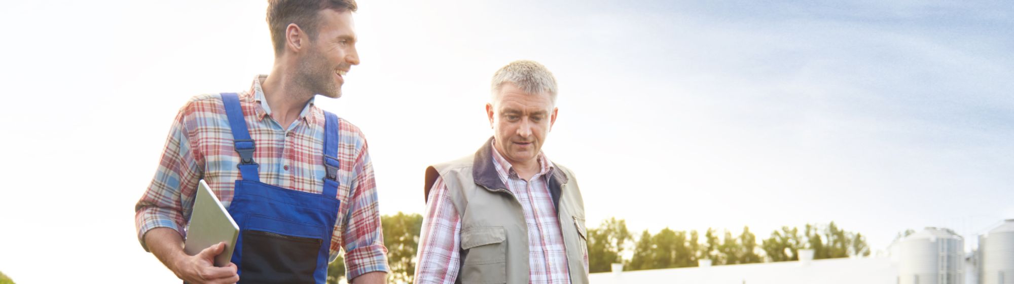 Two farmers walking through a large-scale farming operation, sharing their experiences.