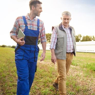 Deux agriculteurs en train de parcourir une exploitation de grandes cultures qui échangent leurs retours d’expérience.