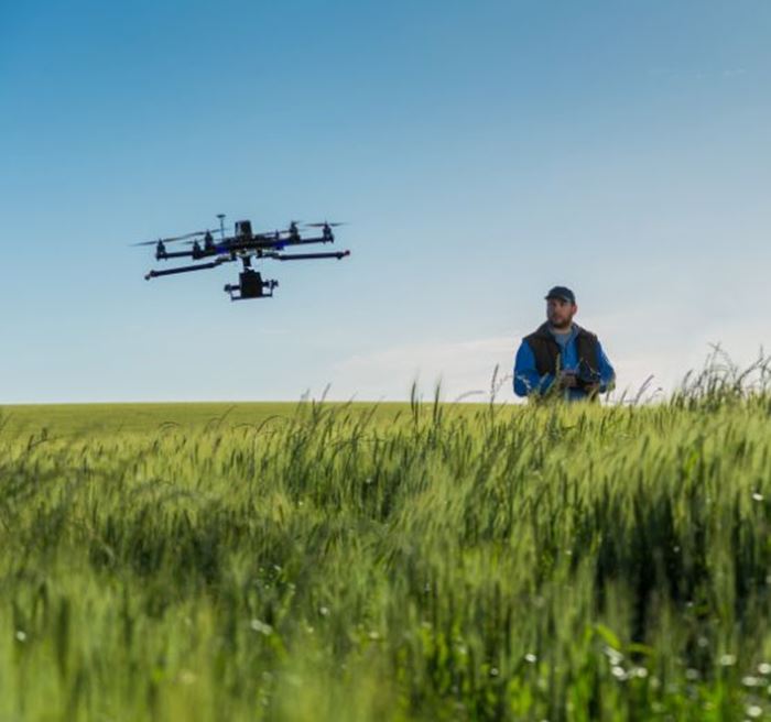 A farmers in a field flying a drone over their ploto