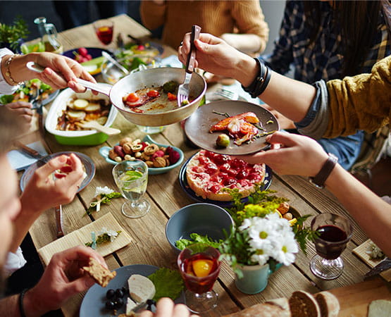 une table de repas garnie en nourriture avec des gens autour